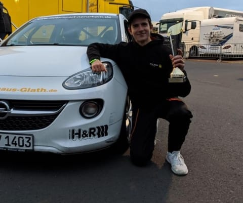 Foto von Adrian nach seinem 2. Platz beim Bundesendlauf im Youngster Cup, mit Pokal und einem der Rennfahrzeuge.